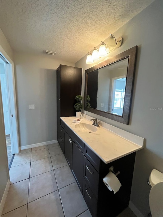 bathroom with tile patterned flooring, vanity, a textured ceiling, and toilet