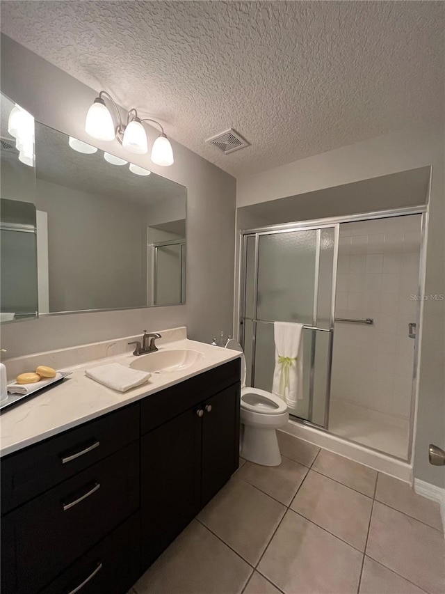 bathroom featuring vanity, a textured ceiling, a shower with door, tile patterned flooring, and toilet