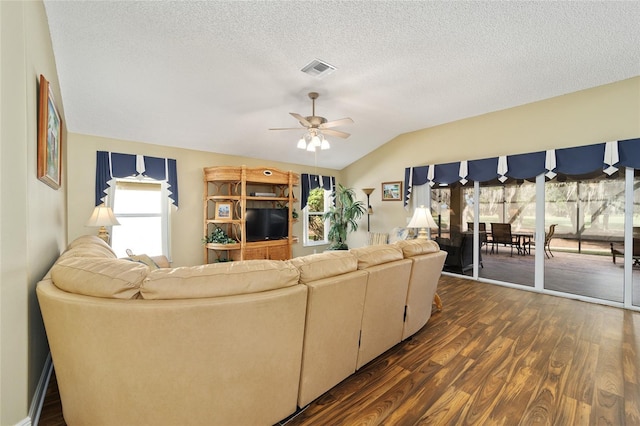 living room featuring a wealth of natural light, dark hardwood / wood-style flooring, ceiling fan, and vaulted ceiling