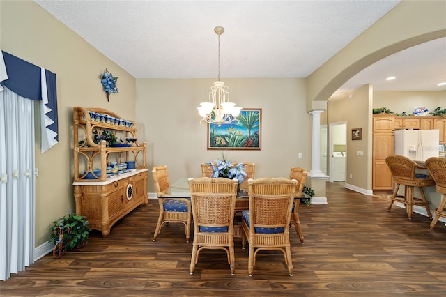 dining room with ornate columns, dark hardwood / wood-style floors, a chandelier, a textured ceiling, and washer / dryer