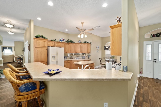 kitchen with white refrigerator with ice dispenser, dark hardwood / wood-style floors, ceiling fan, a textured ceiling, and kitchen peninsula