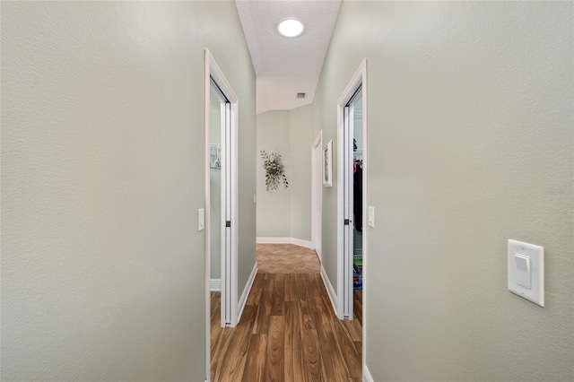 hallway featuring a textured ceiling and dark hardwood / wood-style floors