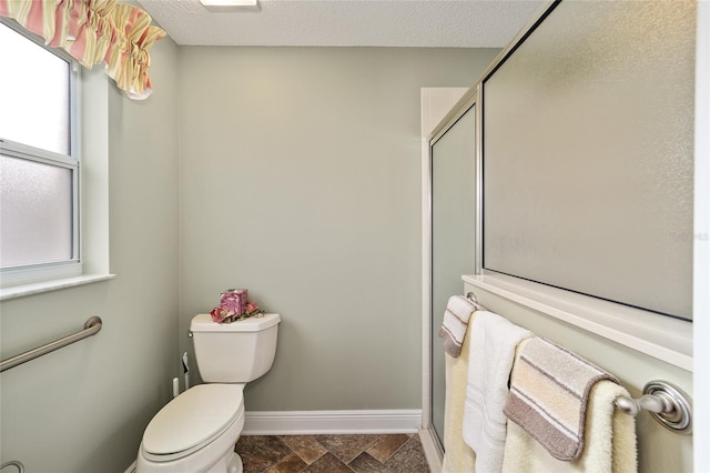 bathroom with an enclosed shower, toilet, and a textured ceiling