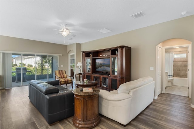 living room featuring a textured ceiling, ceiling fan, and dark wood-type flooring