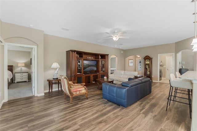 living room featuring ceiling fan and dark hardwood / wood-style flooring