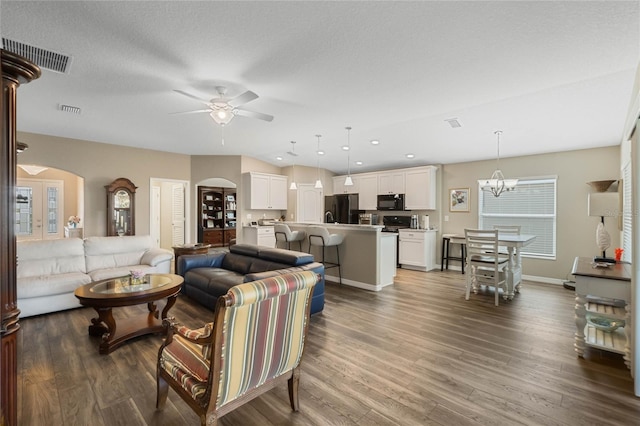 living room featuring a textured ceiling, dark hardwood / wood-style floors, and ceiling fan with notable chandelier