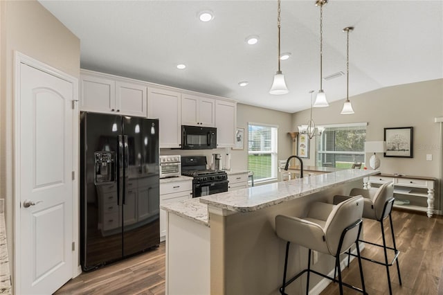 kitchen with a kitchen island with sink, black appliances, pendant lighting, white cabinets, and dark hardwood / wood-style floors