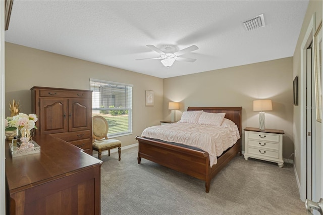 carpeted bedroom with ceiling fan and a textured ceiling