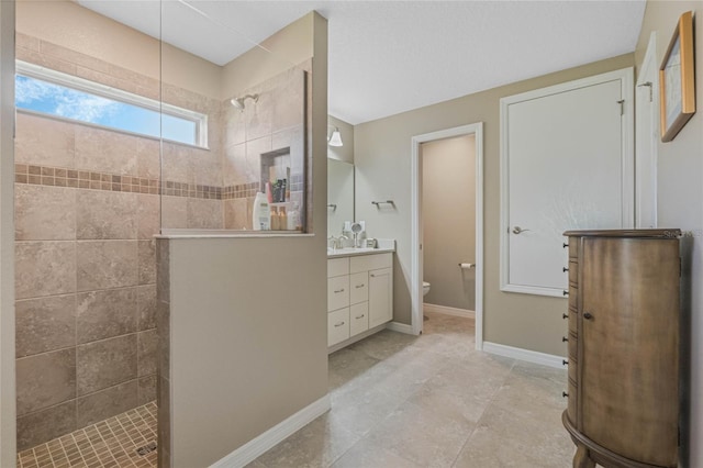 bathroom with tile patterned floors, vanity, toilet, and tiled shower