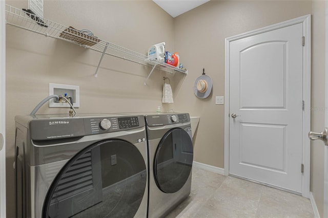 laundry room with washing machine and clothes dryer and light tile patterned floors