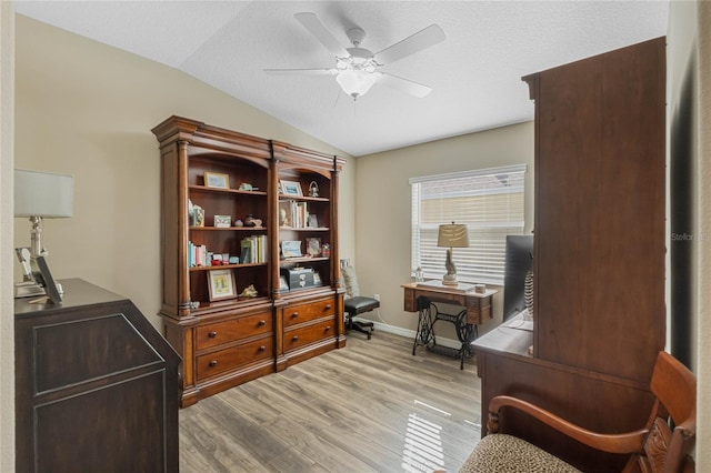 living area with ceiling fan, light hardwood / wood-style floors, a textured ceiling, and vaulted ceiling