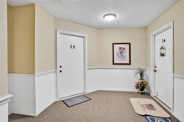 carpeted entrance foyer with a textured ceiling