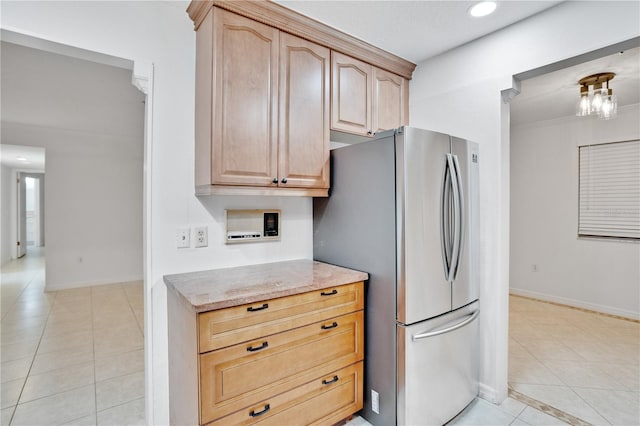 kitchen featuring stainless steel fridge, light stone countertops, light tile patterned floors, and light brown cabinetry