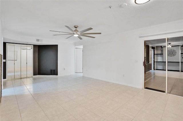 tiled empty room with ceiling fan and ornamental molding