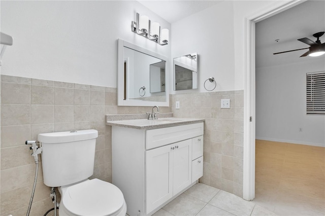 bathroom featuring ceiling fan, tile patterned flooring, toilet, vanity, and tile walls