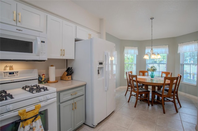 kitchen featuring pendant lighting, white appliances, a notable chandelier, light tile patterned flooring, and white cabinetry