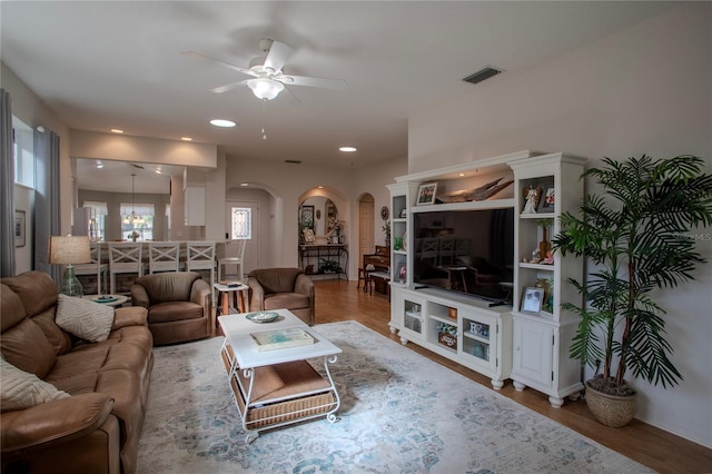 living room featuring ceiling fan with notable chandelier and hardwood / wood-style flooring