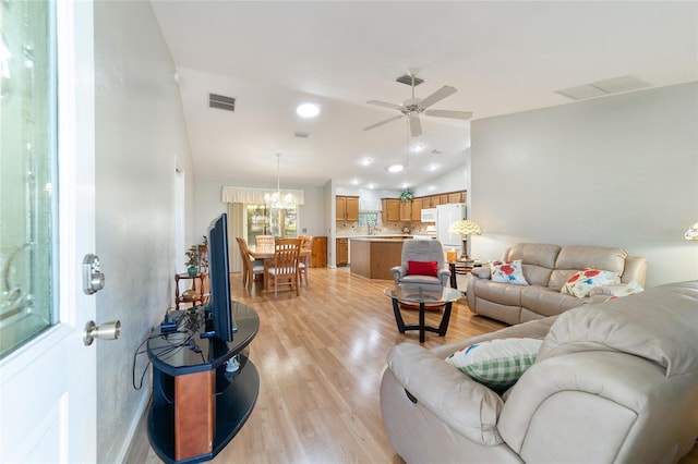 living room featuring ceiling fan with notable chandelier and light hardwood / wood-style flooring