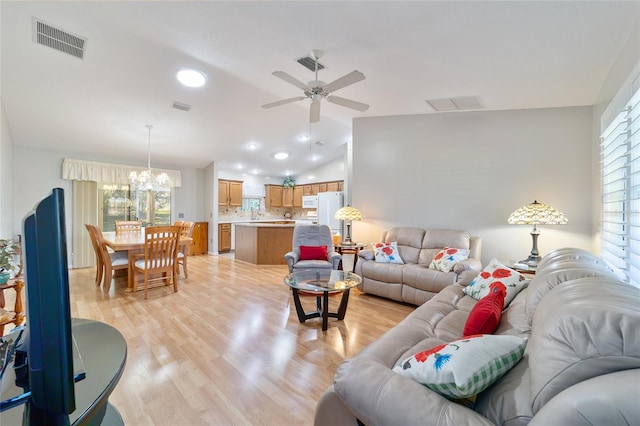 living room with vaulted ceiling, plenty of natural light, light hardwood / wood-style floors, and ceiling fan with notable chandelier