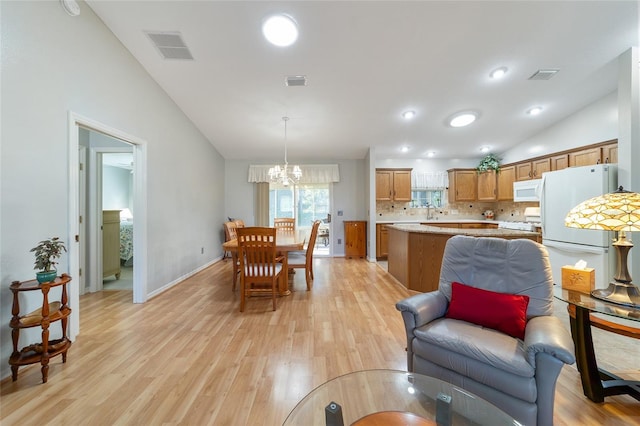 interior space with light hardwood / wood-style floors, an inviting chandelier, lofted ceiling, and sink