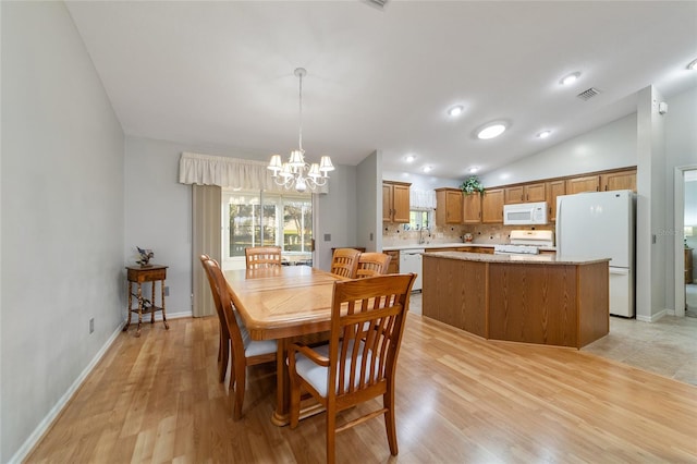 dining space with light hardwood / wood-style flooring, a chandelier, and vaulted ceiling