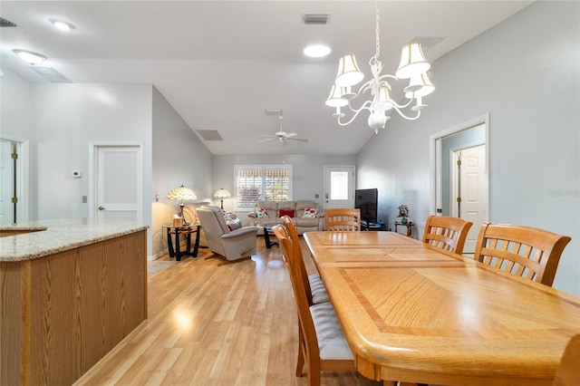 dining space with ceiling fan with notable chandelier, light wood-type flooring, and lofted ceiling