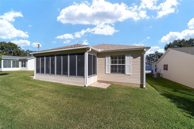 rear view of house featuring a sunroom, a yard, and cooling unit