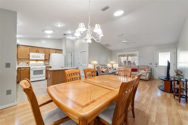 dining room featuring ceiling fan with notable chandelier, light hardwood / wood-style flooring, and lofted ceiling