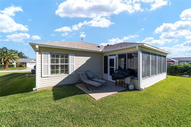 rear view of house with a patio, a lawn, and a sunroom