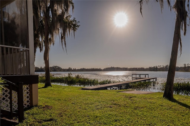 view of dock with a yard and a water view