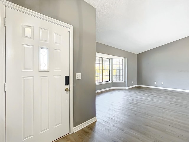 foyer entrance featuring wood-type flooring, a textured ceiling, and lofted ceiling