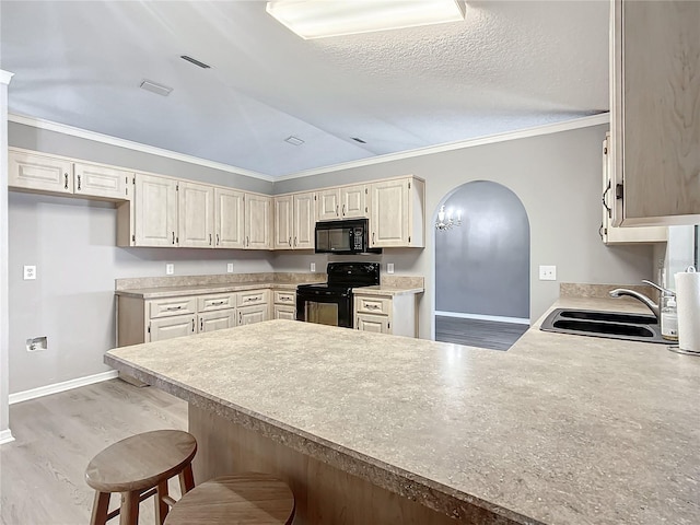 kitchen featuring a breakfast bar, lofted ceiling, black appliances, sink, and kitchen peninsula