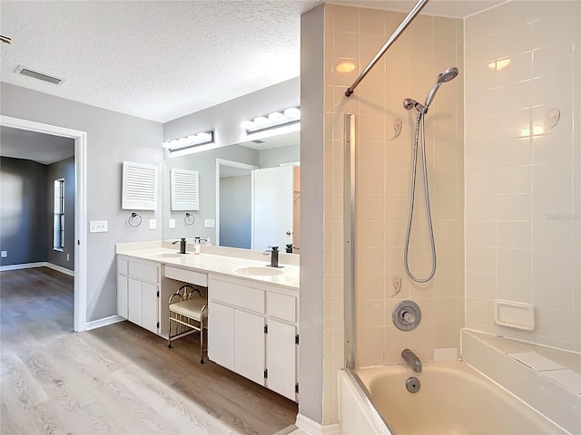 bathroom with hardwood / wood-style flooring, tiled shower / bath combo, a textured ceiling, and vanity