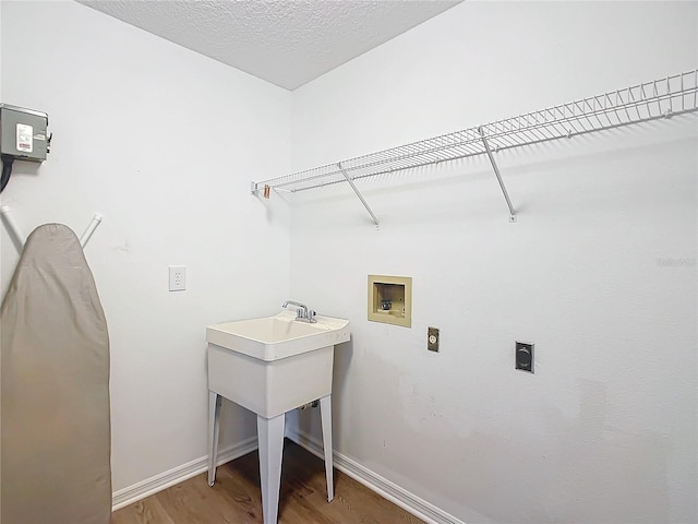 washroom with hookup for an electric dryer, wood-type flooring, a textured ceiling, and hookup for a washing machine