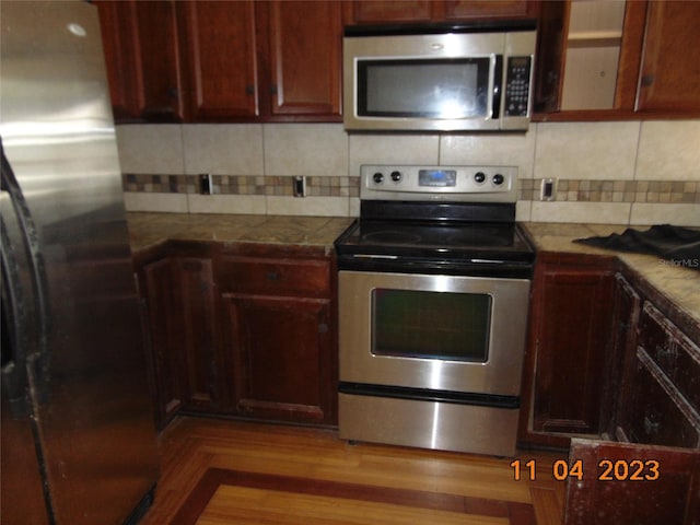 kitchen featuring dark stone counters, decorative backsplash, appliances with stainless steel finishes, and light hardwood / wood-style flooring