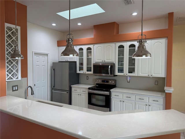 kitchen with sink, hanging light fixtures, a skylight, white cabinetry, and stainless steel appliances