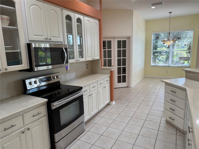 kitchen with white cabinets, pendant lighting, light tile patterned floors, and appliances with stainless steel finishes