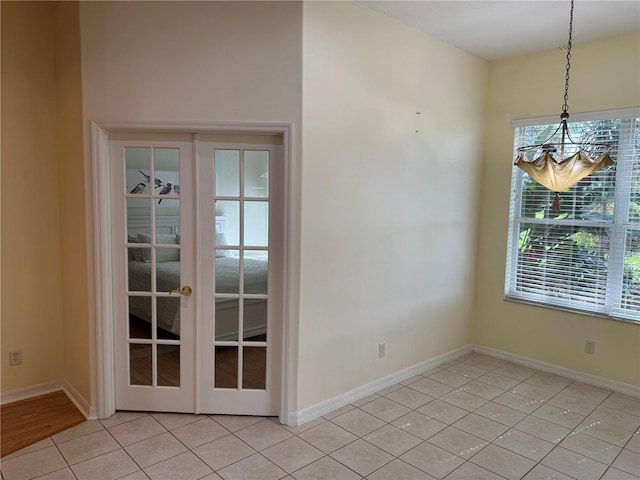 unfurnished dining area with light tile patterned flooring, an inviting chandelier, and french doors