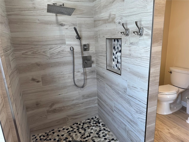 bathroom featuring tiled shower, wood-type flooring, and toilet