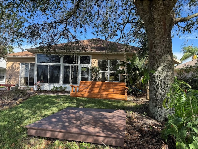 rear view of house featuring a lawn and a sunroom