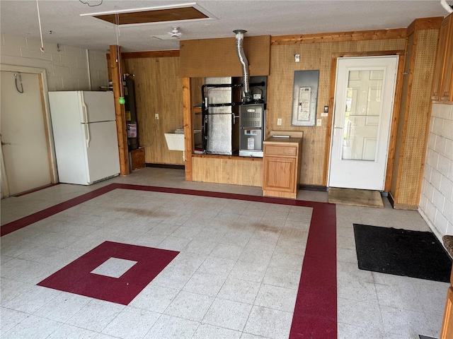 interior space with white refrigerator, electric panel, and heating unit