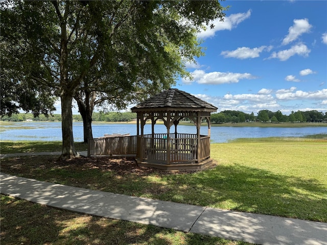 dock area featuring a gazebo, a water view, and a lawn