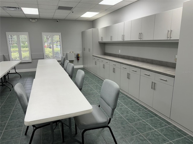 kitchen with a paneled ceiling, white cabinetry, and dark tile patterned flooring