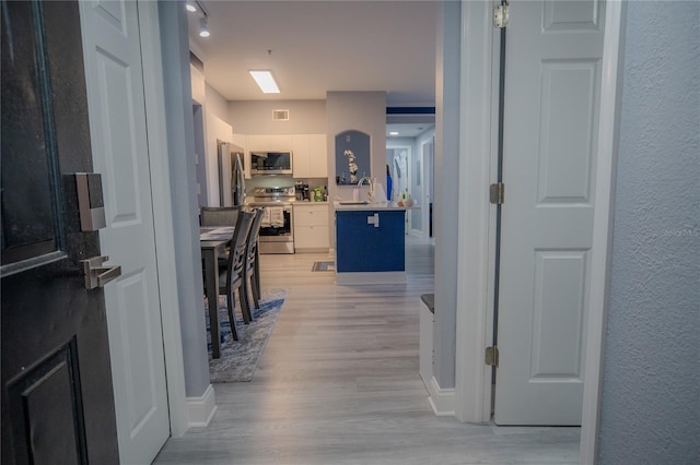 hallway with sink and light hardwood / wood-style floors