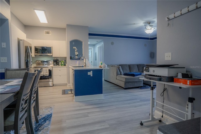 kitchen with appliances with stainless steel finishes, sink, white cabinets, light hardwood / wood-style floors, and a breakfast bar area