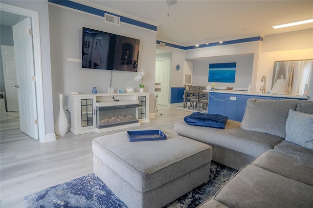 living room featuring light hardwood / wood-style floors and crown molding