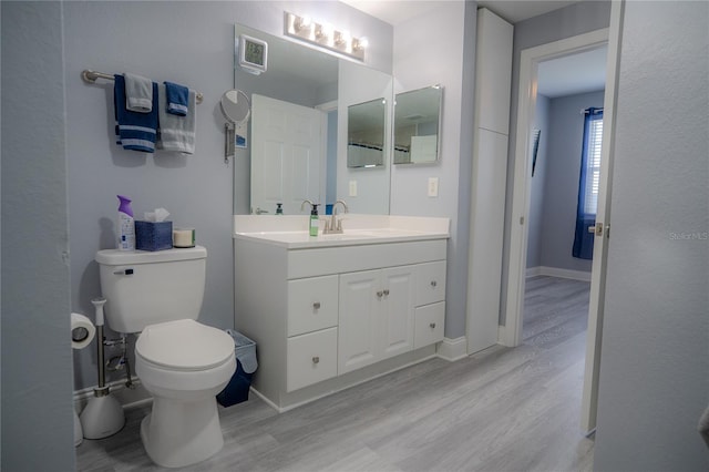 bathroom featuring wood-type flooring, vanity, and toilet