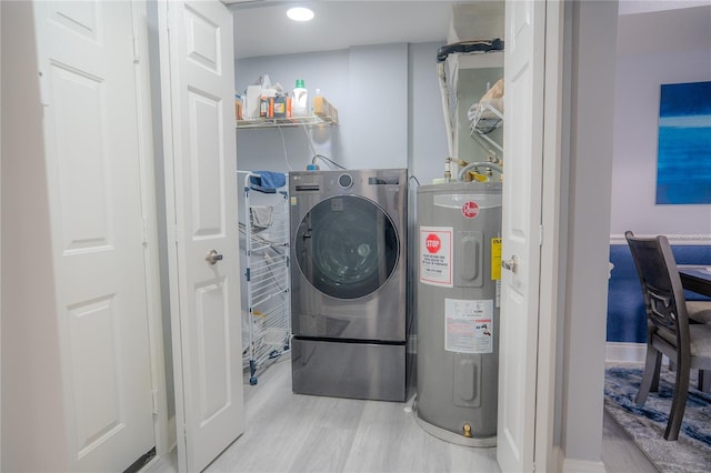 washroom featuring electric water heater, light hardwood / wood-style floors, and washer / clothes dryer