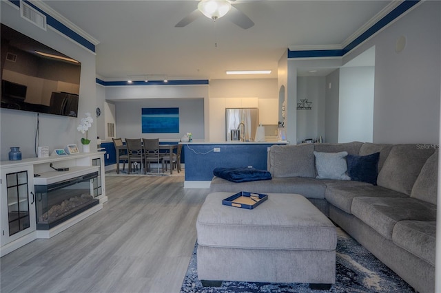 living room with ceiling fan, light hardwood / wood-style flooring, and ornamental molding