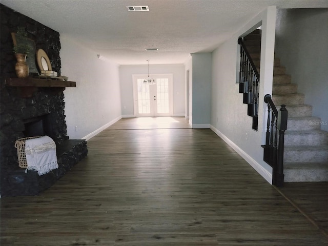 hallway featuring french doors, dark hardwood / wood-style flooring, a textured ceiling, and an inviting chandelier